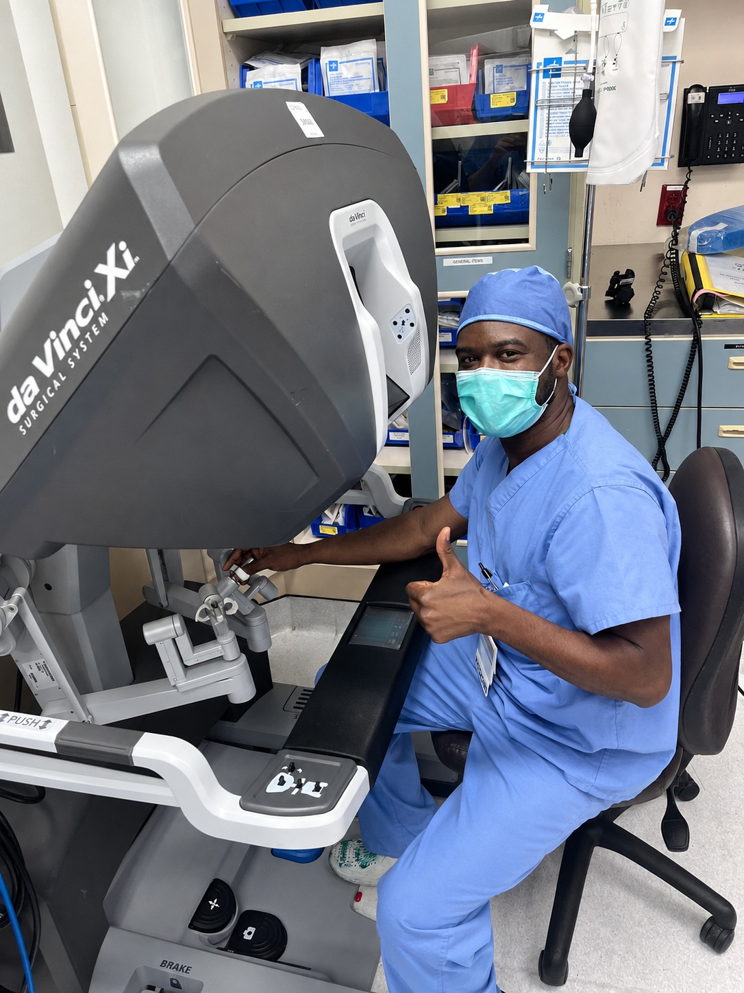 El Dr. Michael Clerveus con ropa quirúrgica junto a una consola de cirujano da Vinci Xi